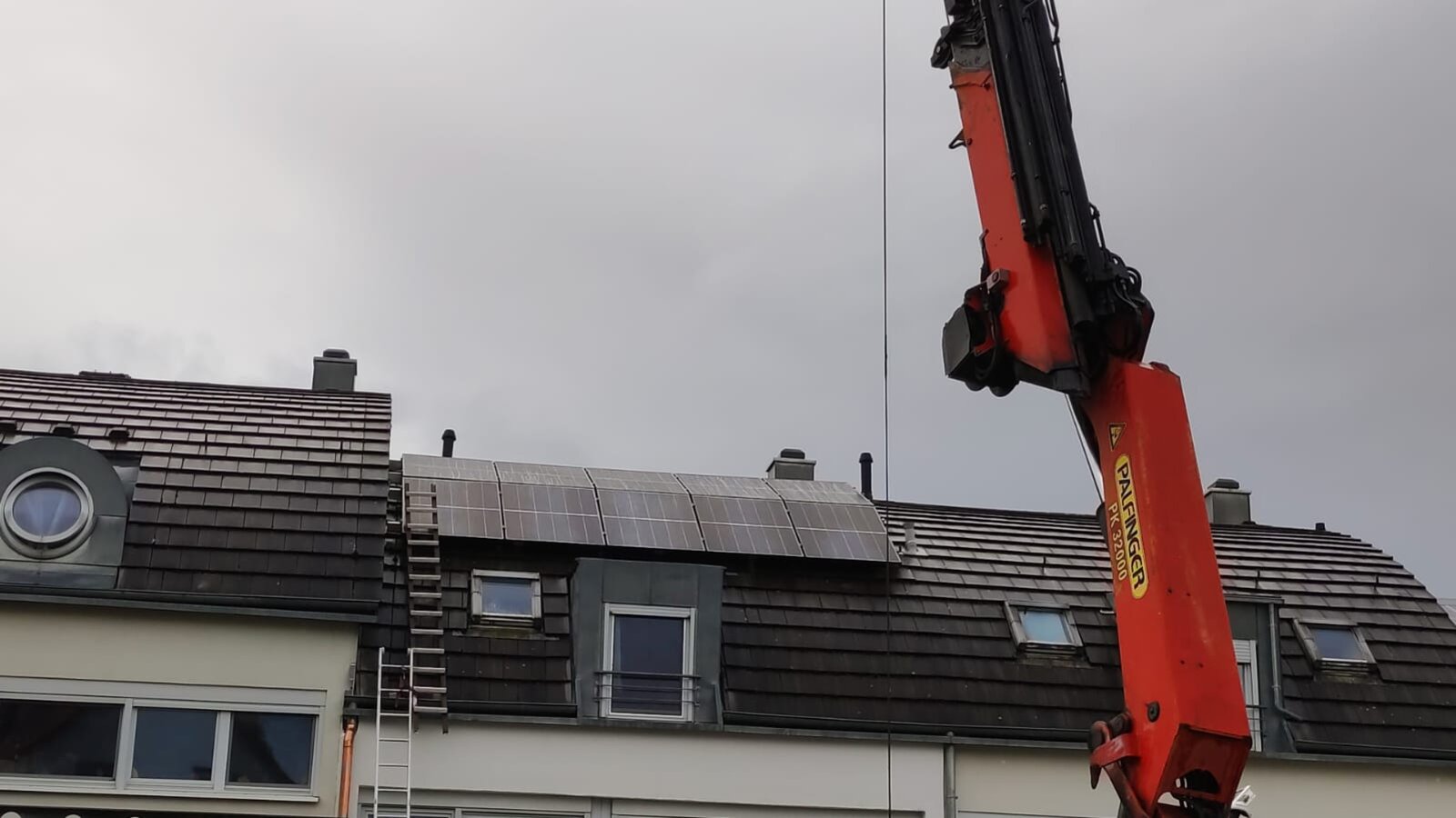 Kranmontage einer Photovoltaikanlage auf einem Reihenhausdach