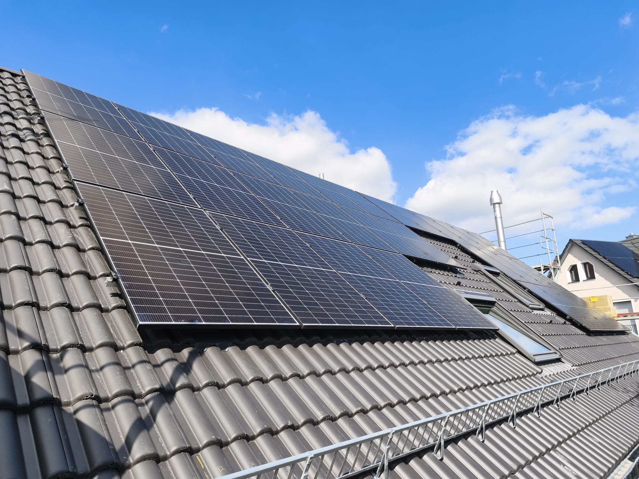 Photovoltaikanlage auf einem Ziegeldach vor blauem Himmel