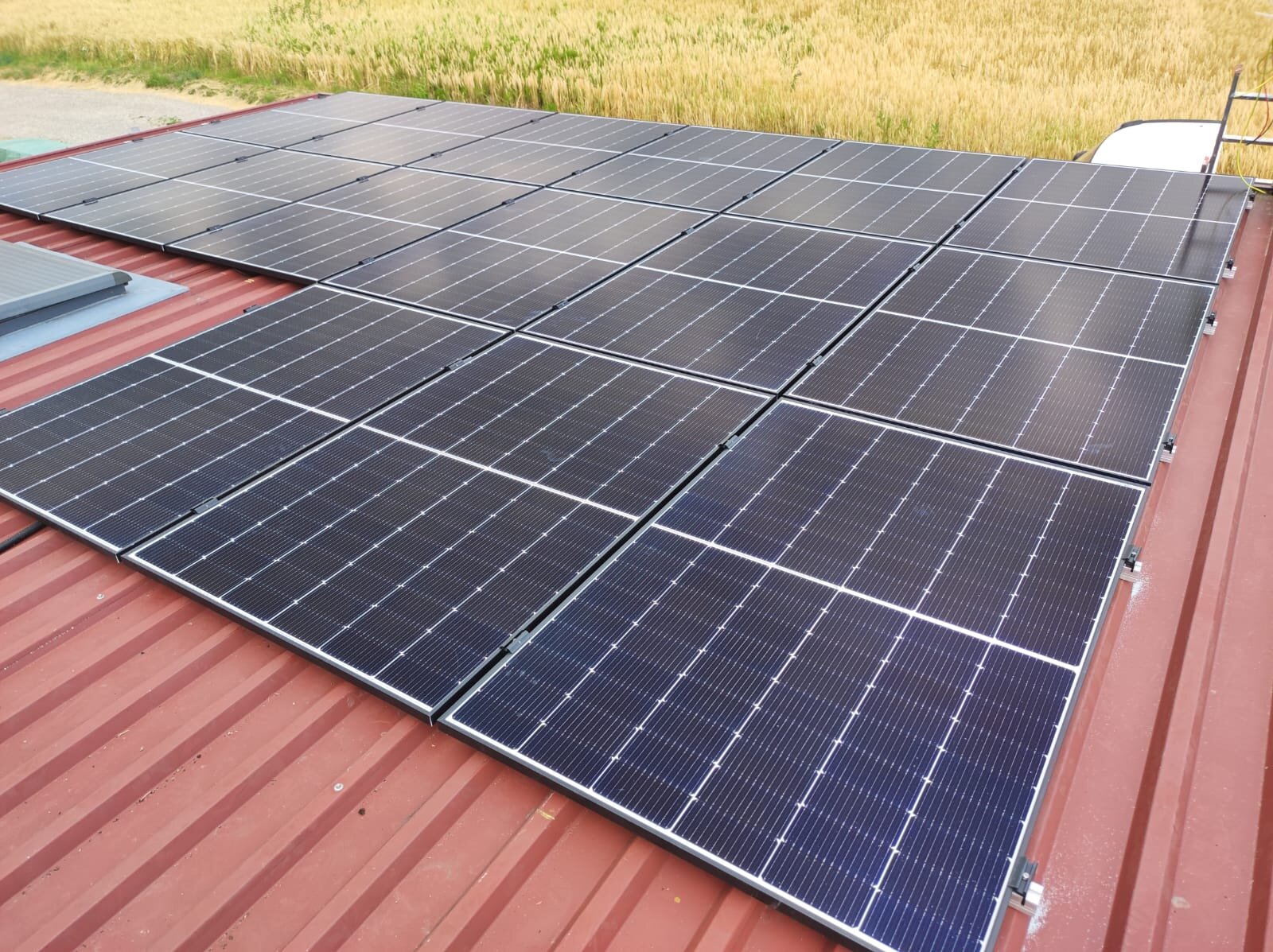 Photovoltaikanlage auf einem Blechdach vor einem Getreidefeld