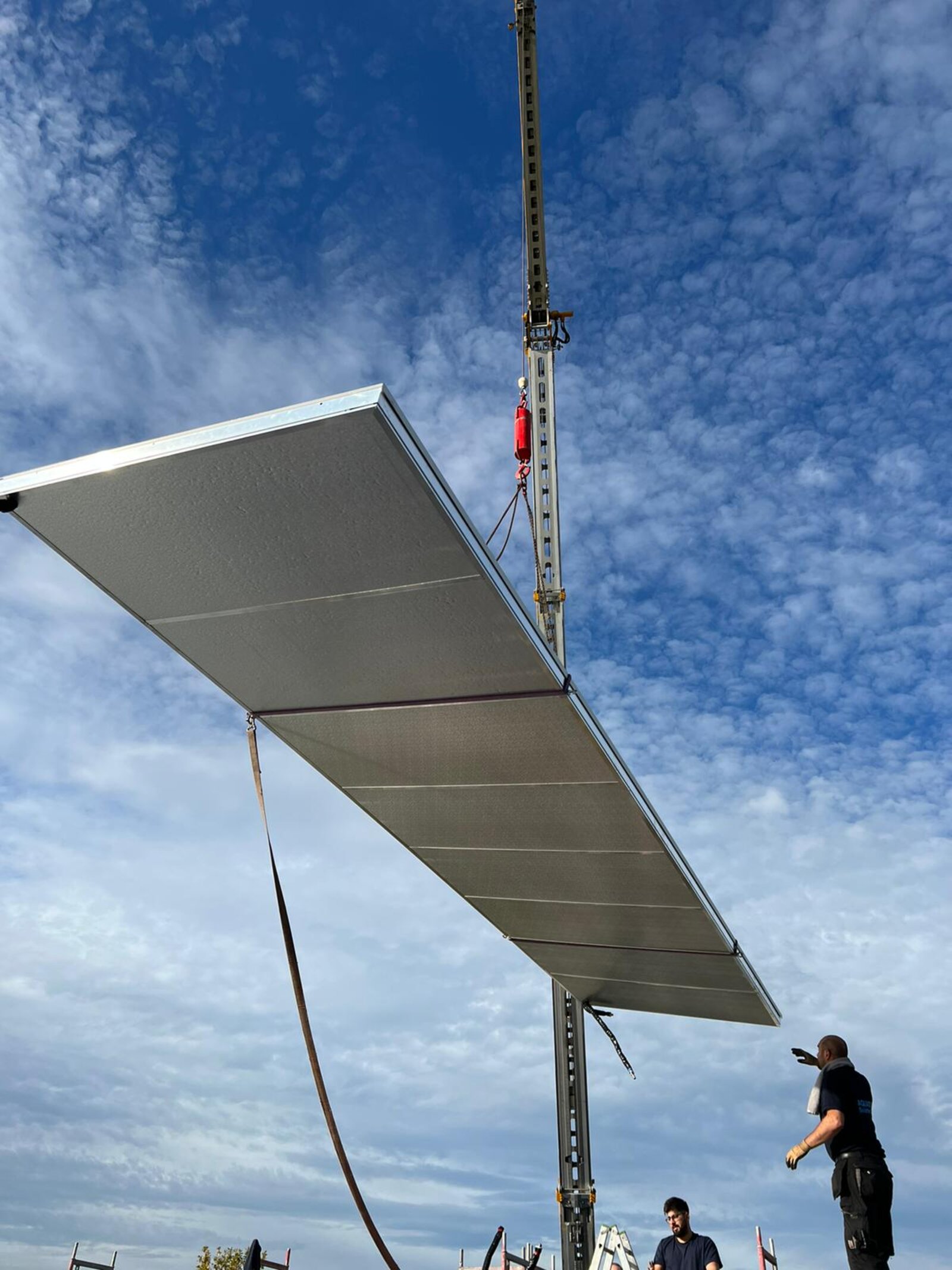 Solarthermie-Kollektor wird per Kran auf ein Dach gehoben